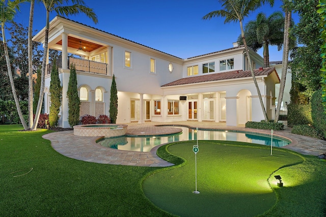 rear view of property with ceiling fan, french doors, a pool with hot tub, a balcony, and a patio area