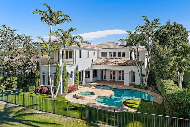 rear view of property with a balcony, a patio area, and a pool with hot tub