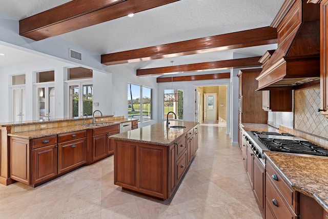 kitchen featuring light stone counters, sink, an island with sink, and stainless steel appliances