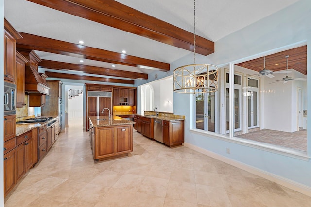 kitchen featuring sink, pendant lighting, built in appliances, beamed ceiling, and an island with sink