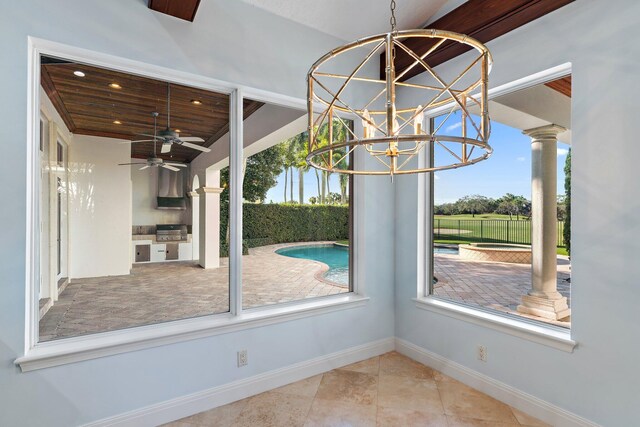 unfurnished dining area with ceiling fan, ornate columns, a wealth of natural light, and wood ceiling