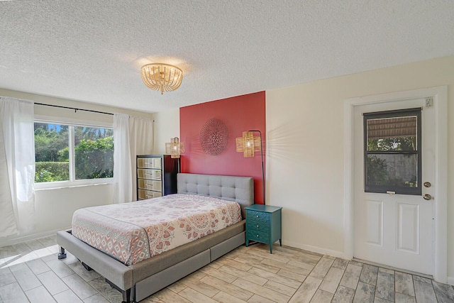 bedroom with baseboards, a textured ceiling, and wood finish floors