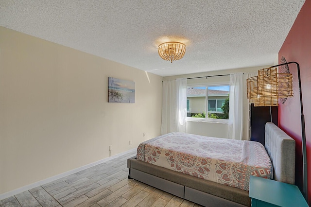 bedroom with light wood-type flooring, a textured ceiling, and baseboards