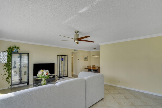 living area featuring a ceiling fan, baseboards, ornamental molding, and a textured ceiling