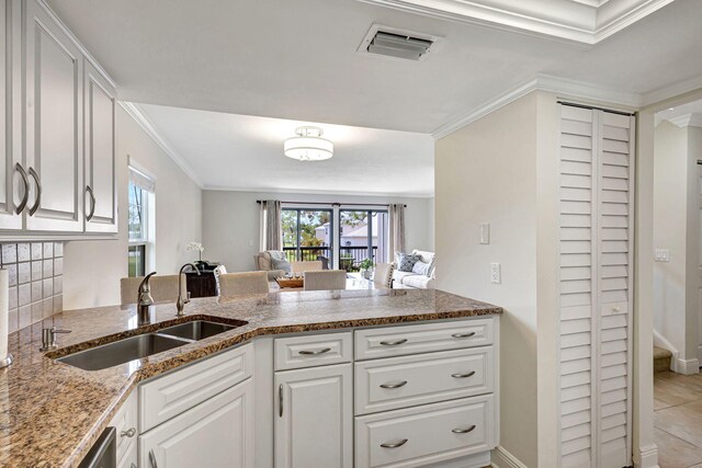 kitchen featuring white cabinets, sink, ornamental molding, stone countertops, and kitchen peninsula