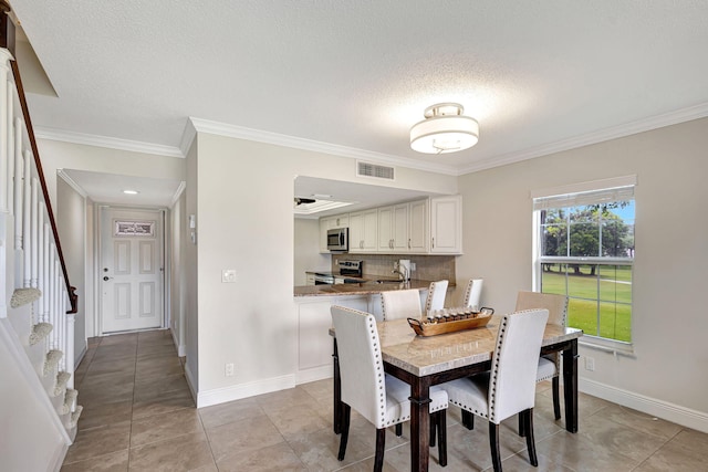 tiled dining area featuring ornamental molding and a textured ceiling