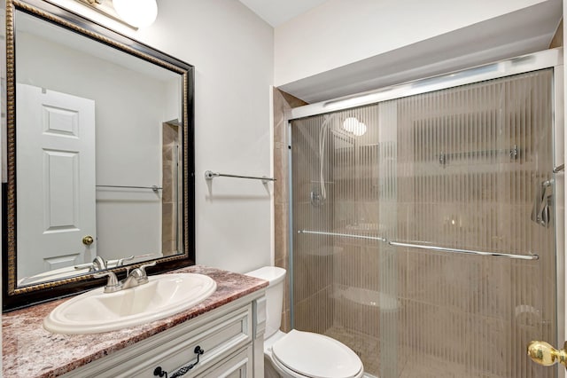 bathroom with vanity, a shower with shower door, and toilet