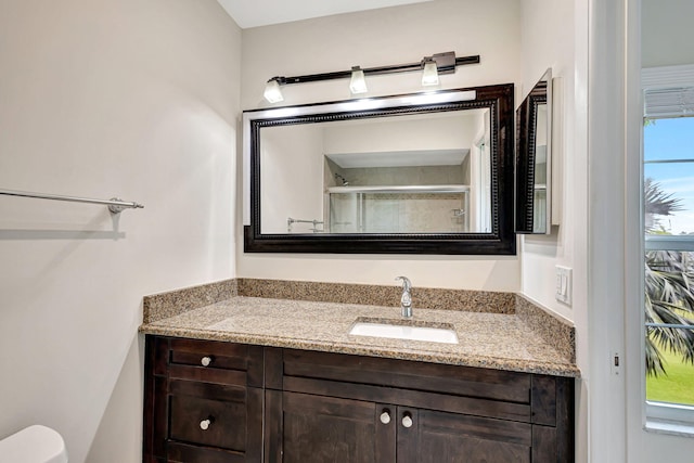 bathroom featuring vanity, a shower with shower door, and toilet