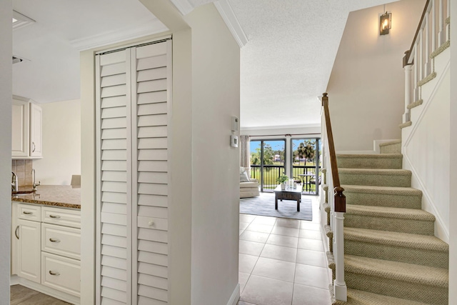 staircase featuring sink, tile patterned floors, crown molding, a textured ceiling, and pool table