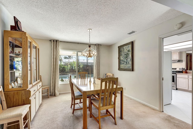 carpeted dining space with a notable chandelier and a textured ceiling