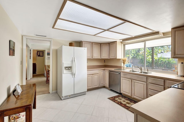 kitchen with dishwasher, white refrigerator with ice dispenser, sink, and light brown cabinetry