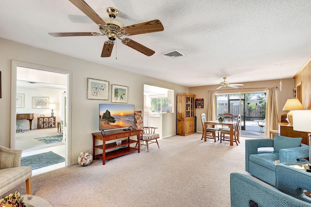 carpeted living room with ceiling fan and a textured ceiling