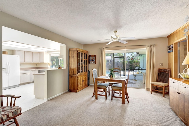 dining area with light carpet, a textured ceiling, ceiling fan, and wooden walls