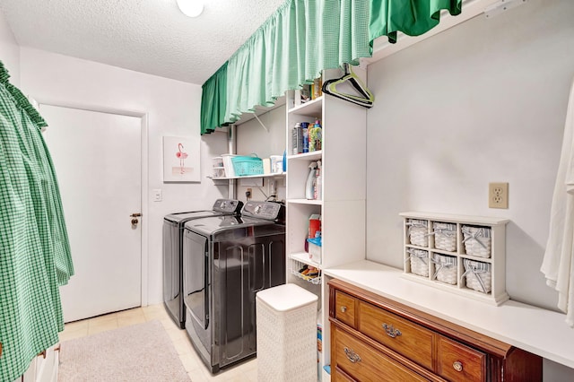 clothes washing area with separate washer and dryer, a textured ceiling, and light tile patterned floors