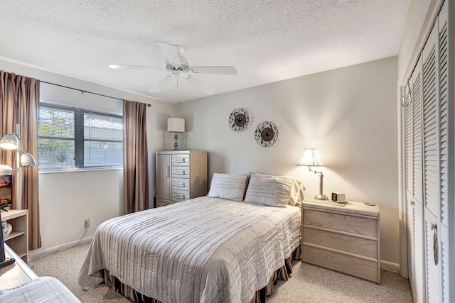 carpeted bedroom with ceiling fan, a textured ceiling, and a closet