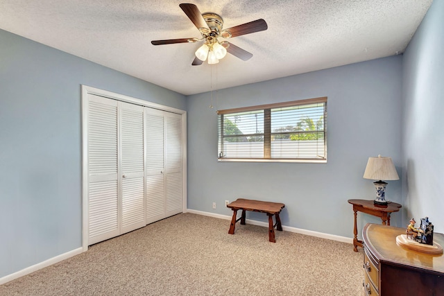 sitting room with a textured ceiling, light colored carpet, and ceiling fan