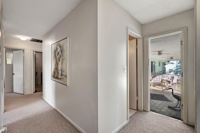 hall with a textured ceiling and light carpet