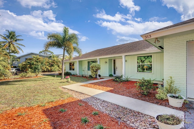 ranch-style house featuring covered porch and a front yard