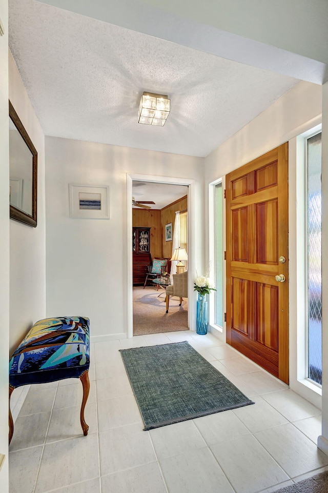 foyer entrance featuring tile patterned floors, wood walls, and a textured ceiling