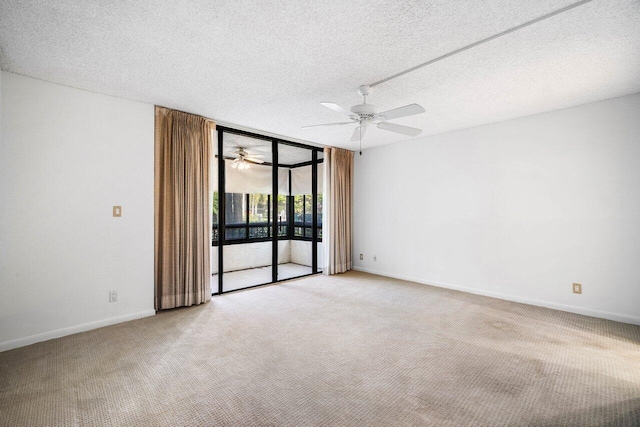 carpeted empty room with ceiling fan, a wall of windows, and a textured ceiling