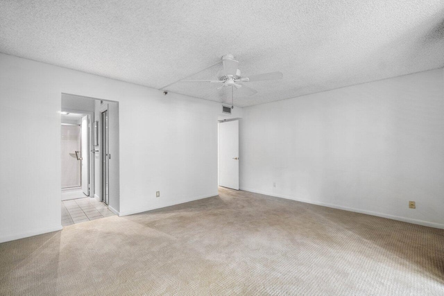 spare room featuring ceiling fan, light colored carpet, and a textured ceiling