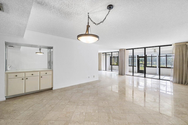 unfurnished living room with a textured ceiling and floor to ceiling windows