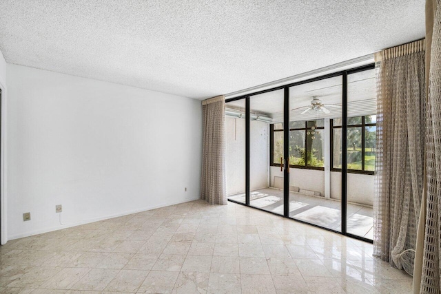 empty room with ceiling fan, a wall of windows, and a textured ceiling