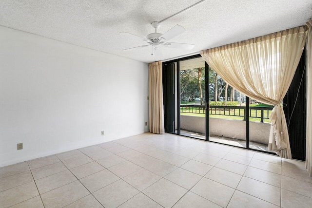 tiled empty room featuring floor to ceiling windows, ceiling fan, and a textured ceiling