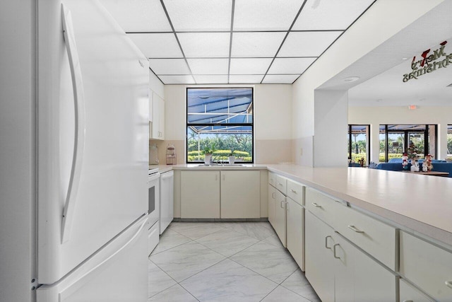 kitchen featuring a drop ceiling, sink, backsplash, kitchen peninsula, and white fridge