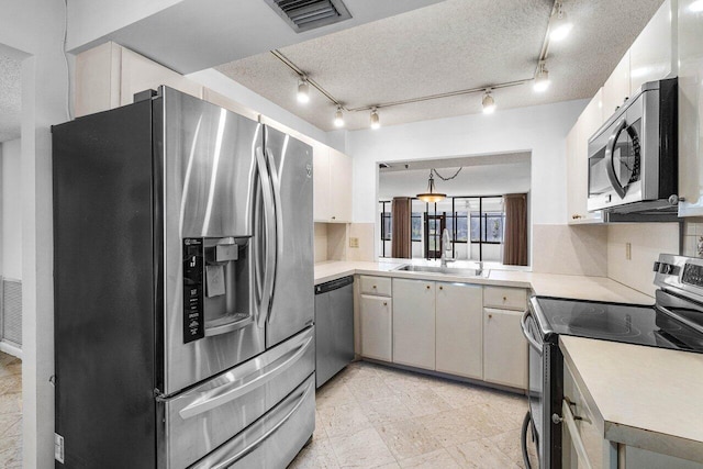 kitchen featuring a textured ceiling, sink, appliances with stainless steel finishes, and tasteful backsplash