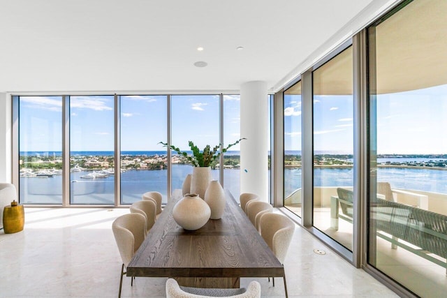 dining space featuring a healthy amount of sunlight, a water view, and a wall of windows