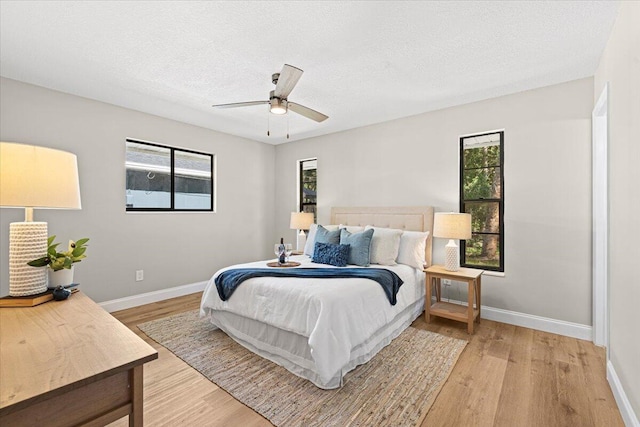 bedroom with multiple windows, a textured ceiling, light hardwood / wood-style flooring, and ceiling fan