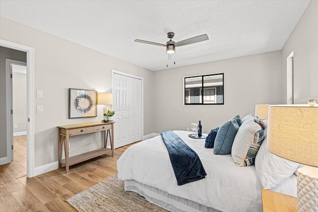 bedroom with ceiling fan, a closet, a textured ceiling, and light hardwood / wood-style flooring