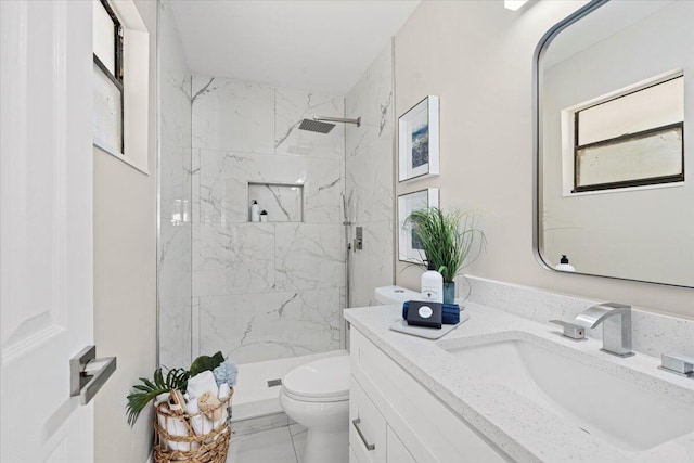 bathroom featuring a tile shower, vanity, and toilet