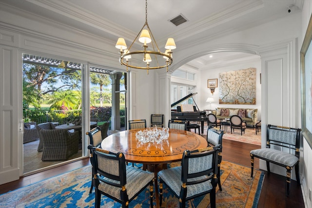 dining space featuring dark hardwood / wood-style flooring, crown molding, and an inviting chandelier