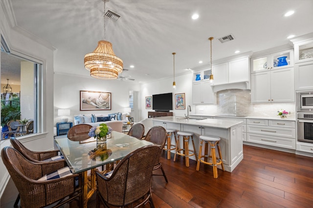 dining room with ceiling fan with notable chandelier, dark hardwood / wood-style flooring, ornamental molding, and sink