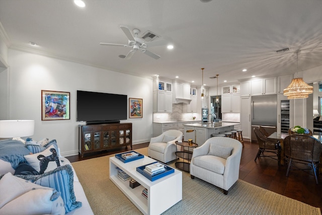 living room with dark hardwood / wood-style flooring, ceiling fan with notable chandelier, and ornamental molding