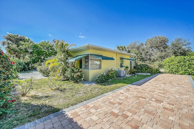 view of side of property with a lawn and central air condition unit