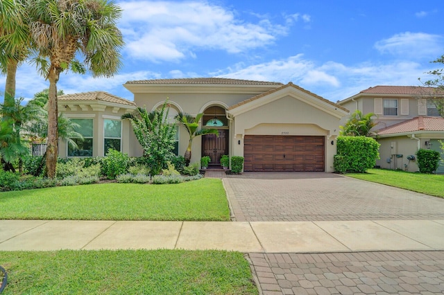 mediterranean / spanish home featuring a garage and a front lawn