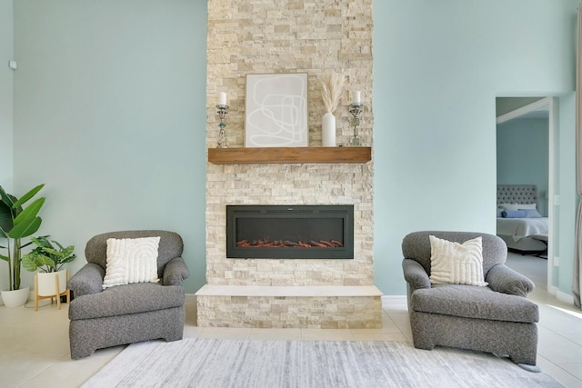 sitting room with tile patterned floors and a stone fireplace