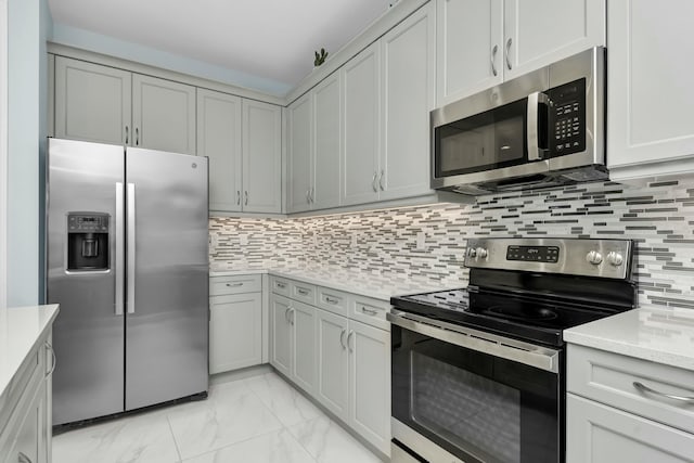 kitchen with tasteful backsplash, appliances with stainless steel finishes, and gray cabinets