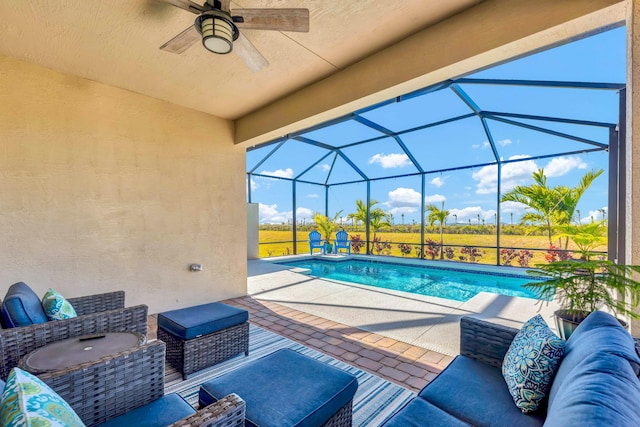 view of pool with an outdoor living space, a patio, a lanai, and ceiling fan