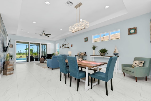 dining room with ceiling fan, a raised ceiling, and a wealth of natural light