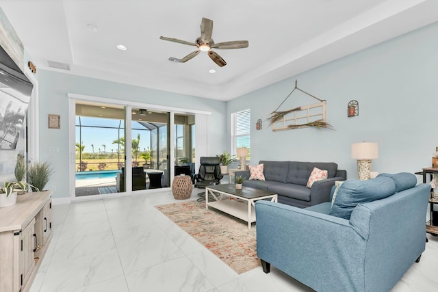 living room featuring ceiling fan and a tray ceiling