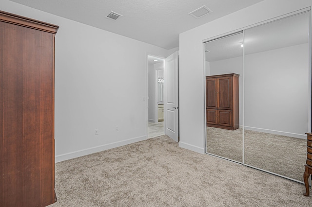 unfurnished bedroom featuring light carpet and a closet