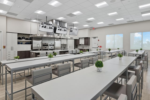 kitchen featuring tasteful backsplash, white cabinets, a large island, a drop ceiling, and light hardwood / wood-style flooring