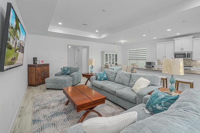 living room featuring a tray ceiling and light hardwood / wood-style floors