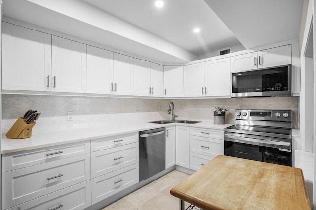 kitchen featuring sink, white cabinetry, light tile patterned flooring, tasteful backsplash, and appliances with stainless steel finishes