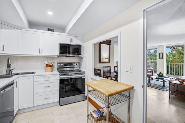 kitchen with stainless steel appliances, white cabinets, and sink