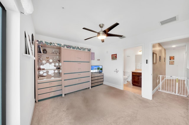 carpeted bedroom with ensuite bathroom and ceiling fan